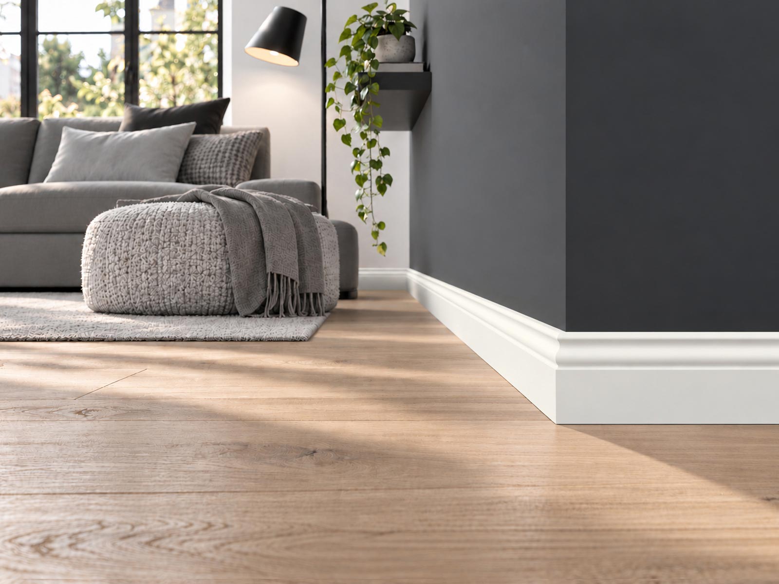 Wohnzimmer mit Holzdielenboden und dunkelgrauer Wand, weiße Hamburger Leiste Pro RAL9010 mit 58 mm am Wandabschluss